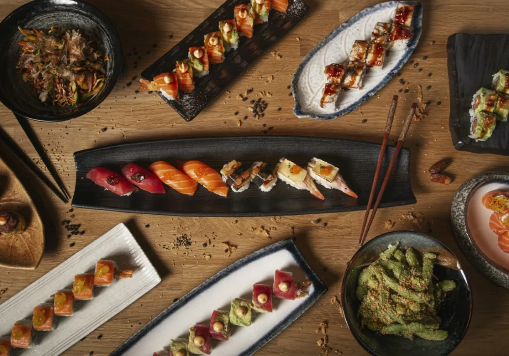 top-view-variety-sushi-nigiri-sashimi-yakisoba-edamame-restaurant-wooden-table (Medium)